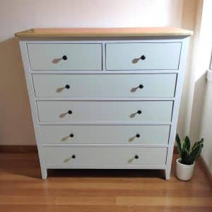 "Cómoda de madera estilo nórdico con cubierta color pino natural y cajones blancos con correderas telescópicas."