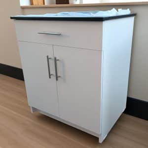 Mueble auxiliar blanco con cubierta de cuarzo negro galaxy, con cajón, puertas con cierre suave y tiradores metálicos modelo Madrid.