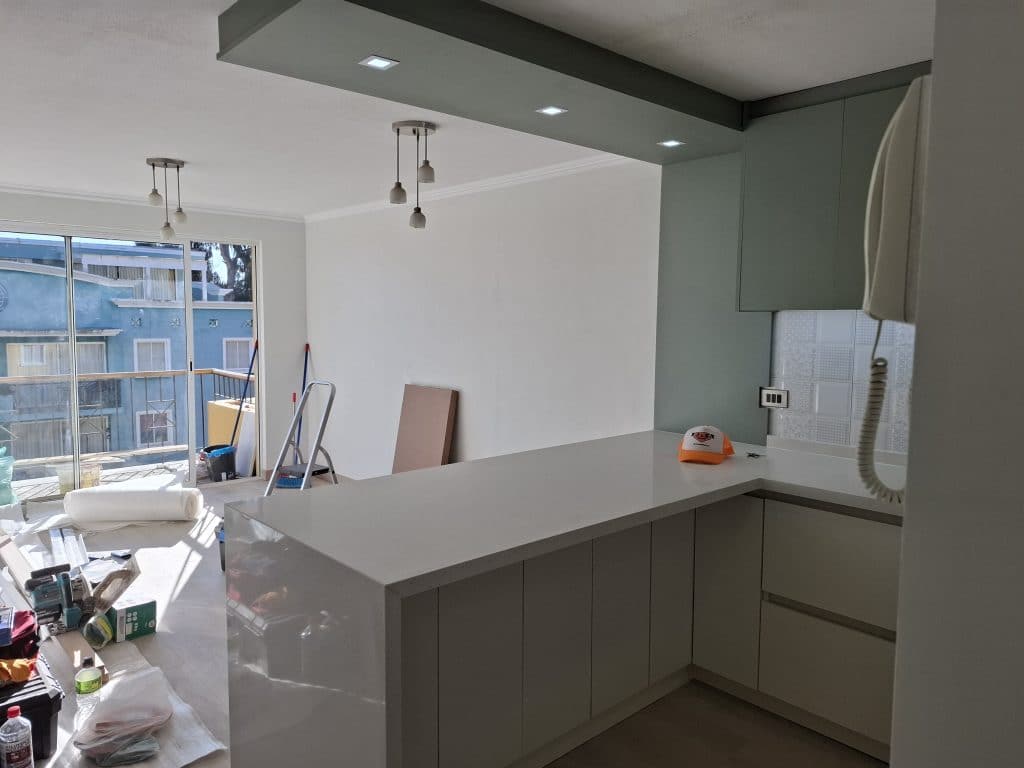 Isla central de cocina con cubierta de cuarzo y muebles de melamina optimizando espacio