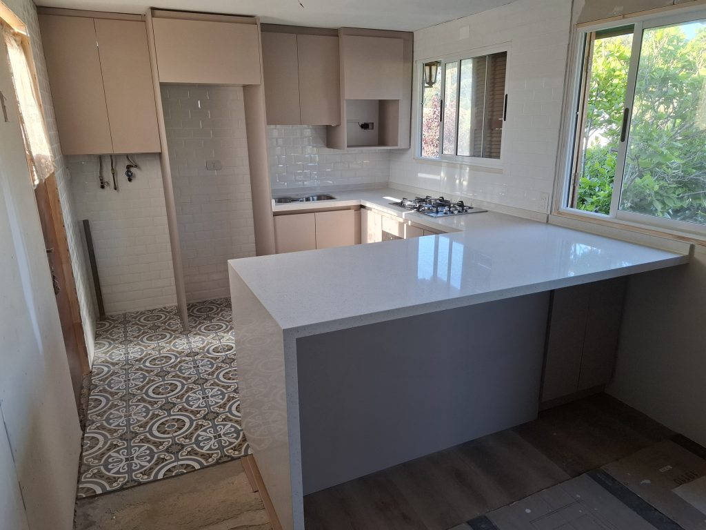 Cocina moderna en melamina taupe con cubierta de cuarzo blanco instalada en El Quisco por JYS Muebles
