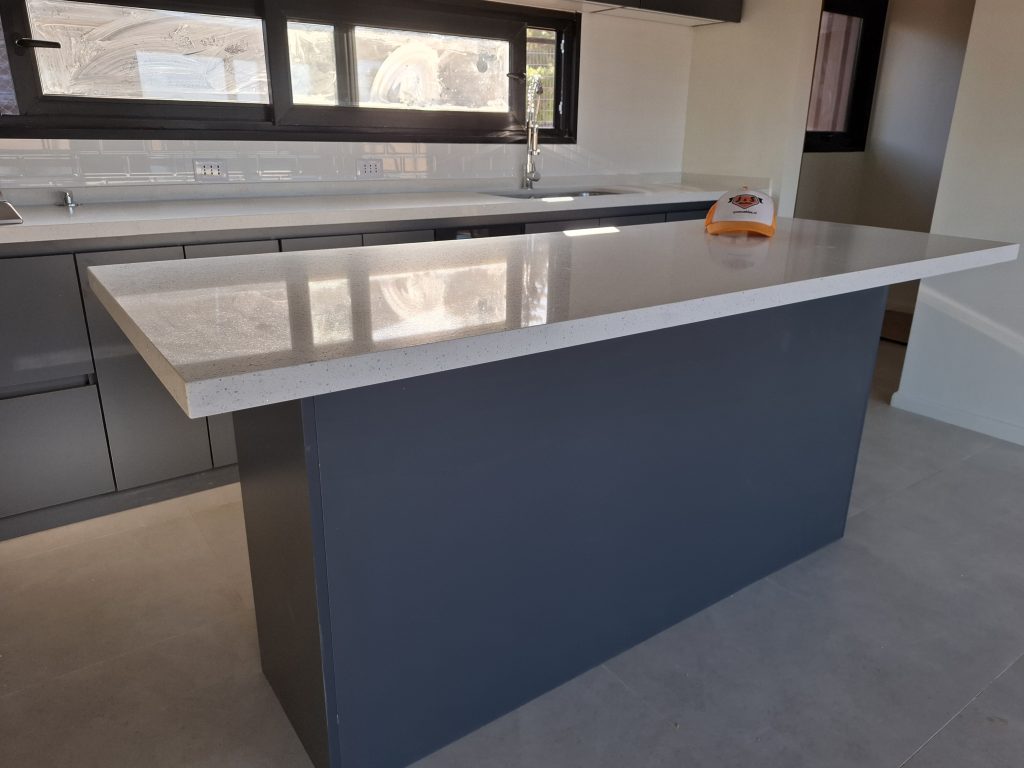 Isla de cocina moderna en El Quisco con muebles gris grafito y cubierta de cuarzo blanco Galaxy