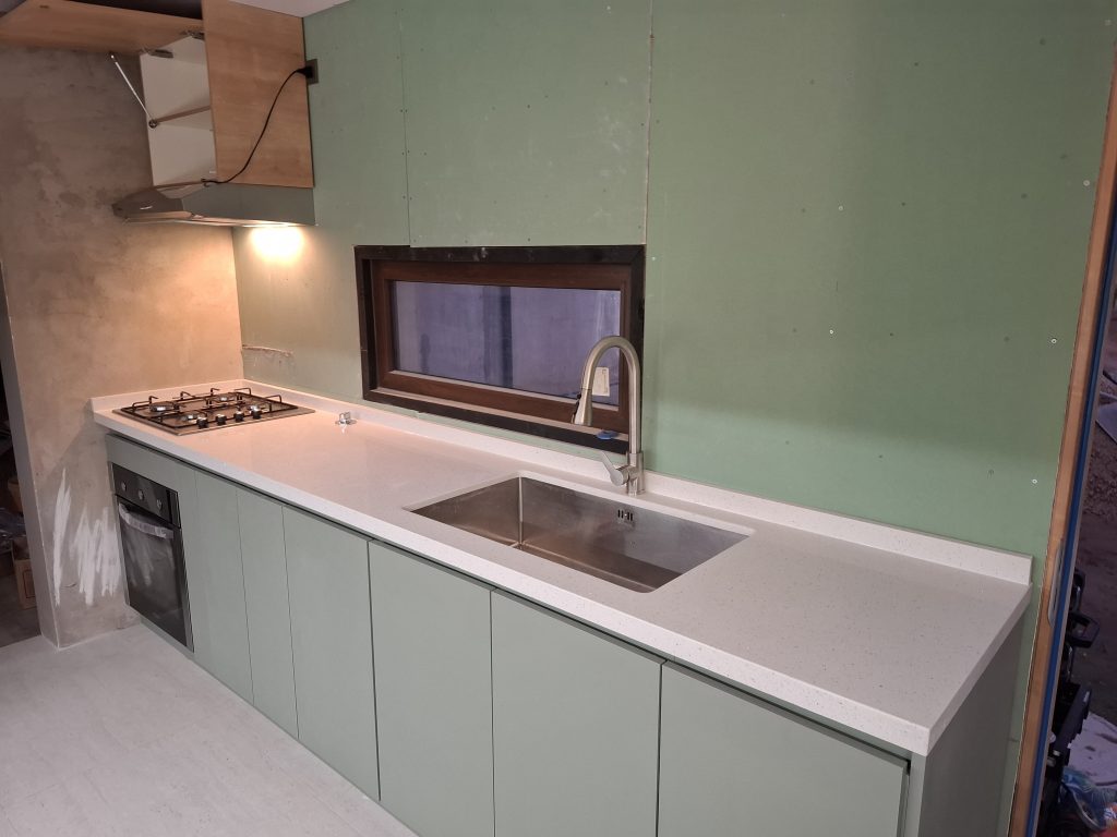Detalle de vitrina con iluminación LED y puertas de vidrio, parte de nuestro proyecto de muebles de cocina a medida en El Quisco con cubiertas de cuarzo de alta resistencia."