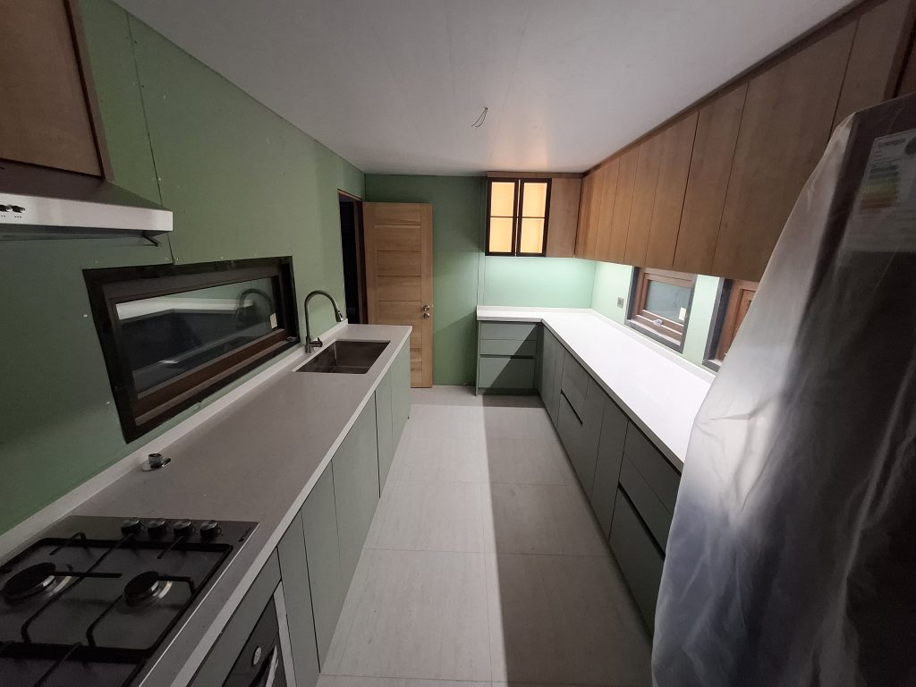 Detalle de vitrina con iluminación LED y puertas de vidrio, parte de nuestro proyecto de muebles de cocina a medida en El Quisco con cubiertas de cuarzo de alta resistencia."