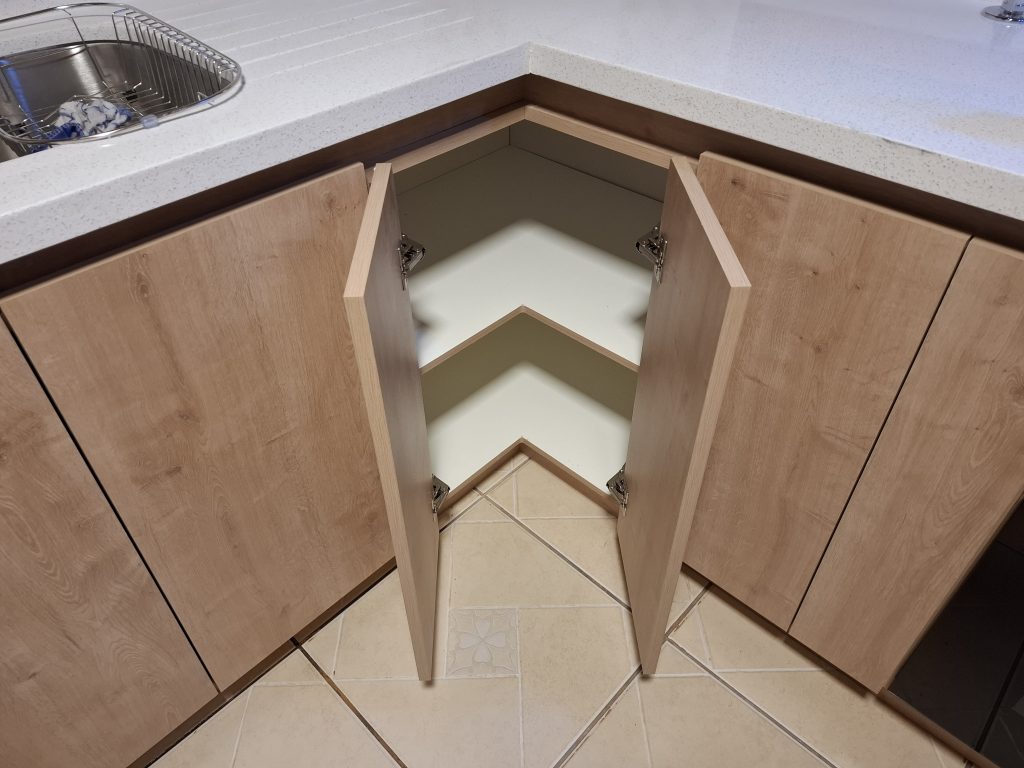 "Detalle de puertas de mueble de cocina con apertura completa para maximizar espacio en esquina."